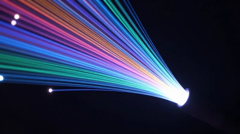 Abstract visualization of multiple vibrant light beams of different colors merging into a single fiber optic cable.